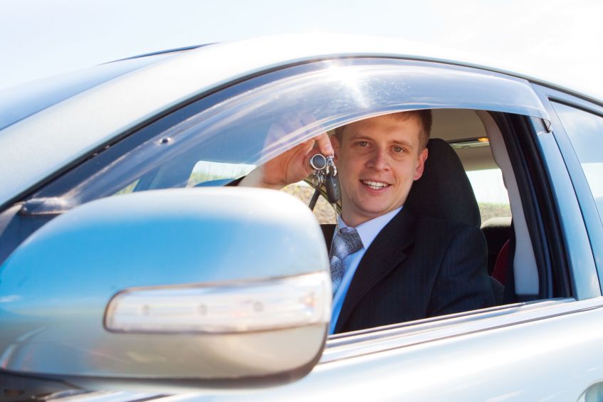 man in suit in car with keys
